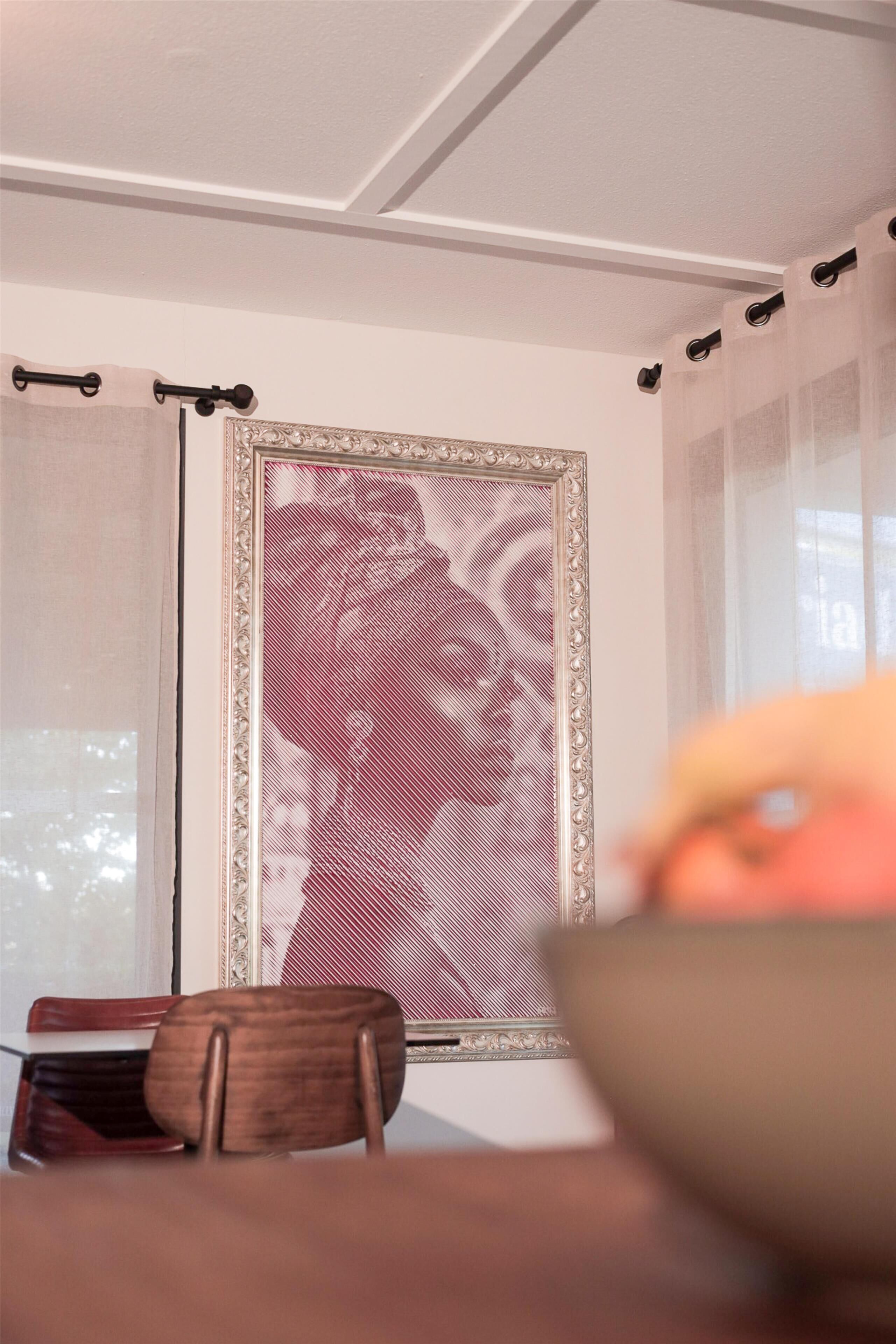 Zona de menjador amb taula, cadires, un mirall decoratiu i una finestra amb cortines.