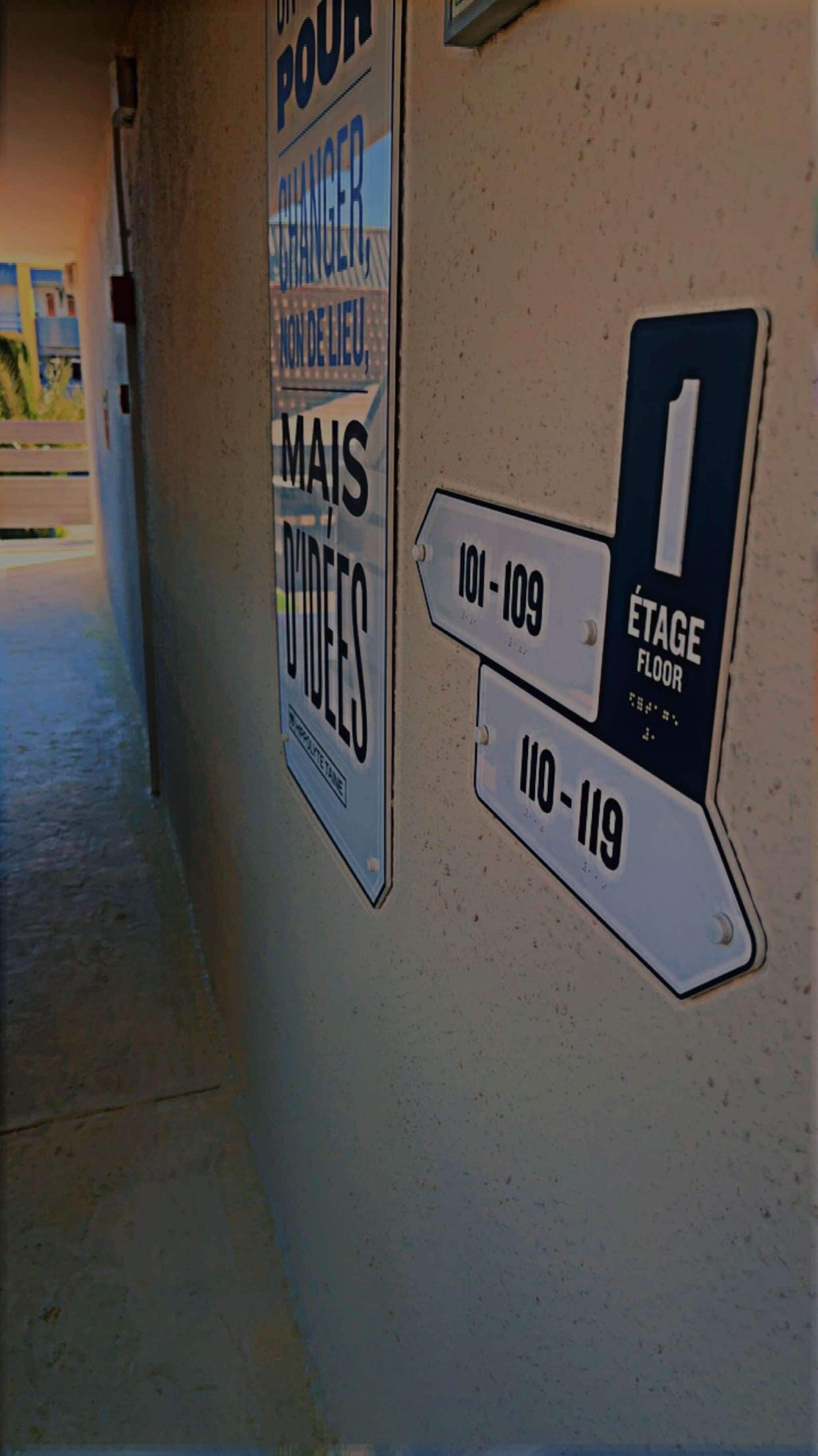 A corridor with directional signs indicating room numbers and a label for the stage floor.