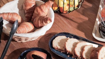 Une table avec des pâtisseries, des fruits et des couverts.