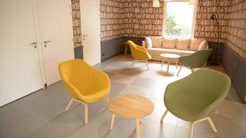 A room with a sofa, two chairs, a small table, and a bookshelf wall.