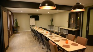 Une salle de conférence avec une longue table, des chaises et des luminaires suspendus.