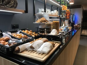 Ein Buffet mit verschiedenen Backwaren, darunter Croissants und Brot, sowie einer Auswahl an Getränken und Soßen.