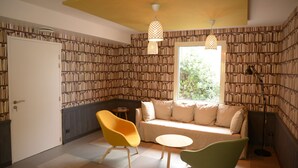 Un coin lecture confortable avec un canapé, deux fauteuils, une petite table et une bibliothèque.