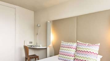 Relax in a stylishly designed room with a geometric patterned pillow, bedside table, and comfortable chair.