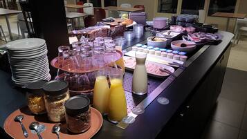Una barra de buffet con diferentes alimentos, bebidas y utensilios.