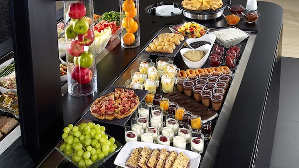 Una mesa de buffet con diferentes opciones de comida, incluyendo frutas, pastelería y postres.