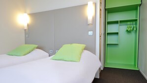 A hotel room with two beds, each with a green pillow, a green wardrobe, and a light switch on the wall. - Campanile Pont A Mousson (Lesmenils)