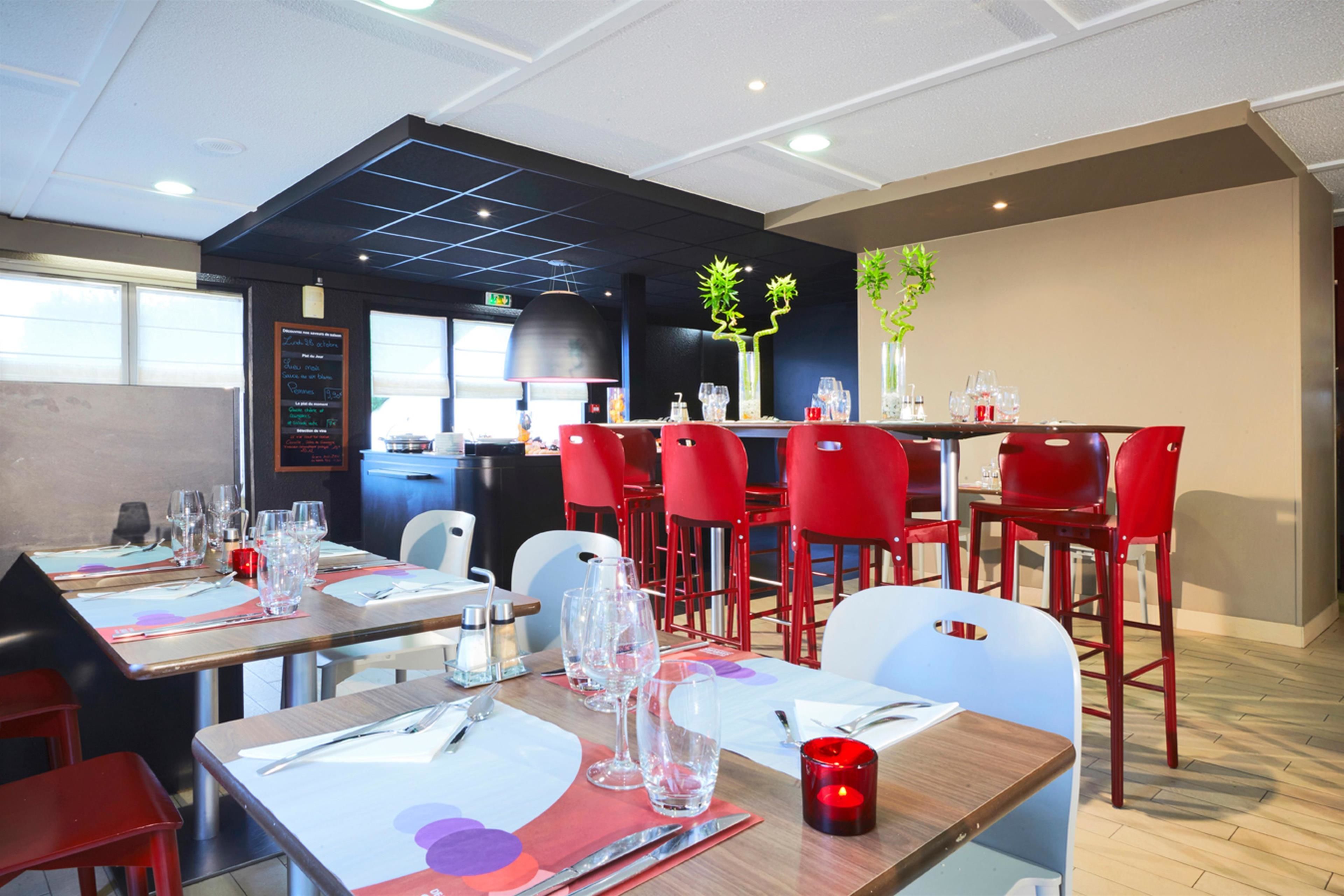 Un restaurante con mesas dispuestas para comer, sillas rojas y una decoración interior moderna.