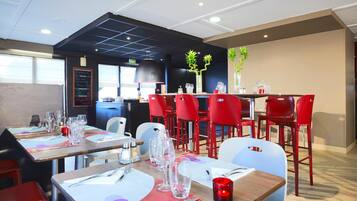 A restaurant with tables set for dining, red chairs, and a modern interior design.