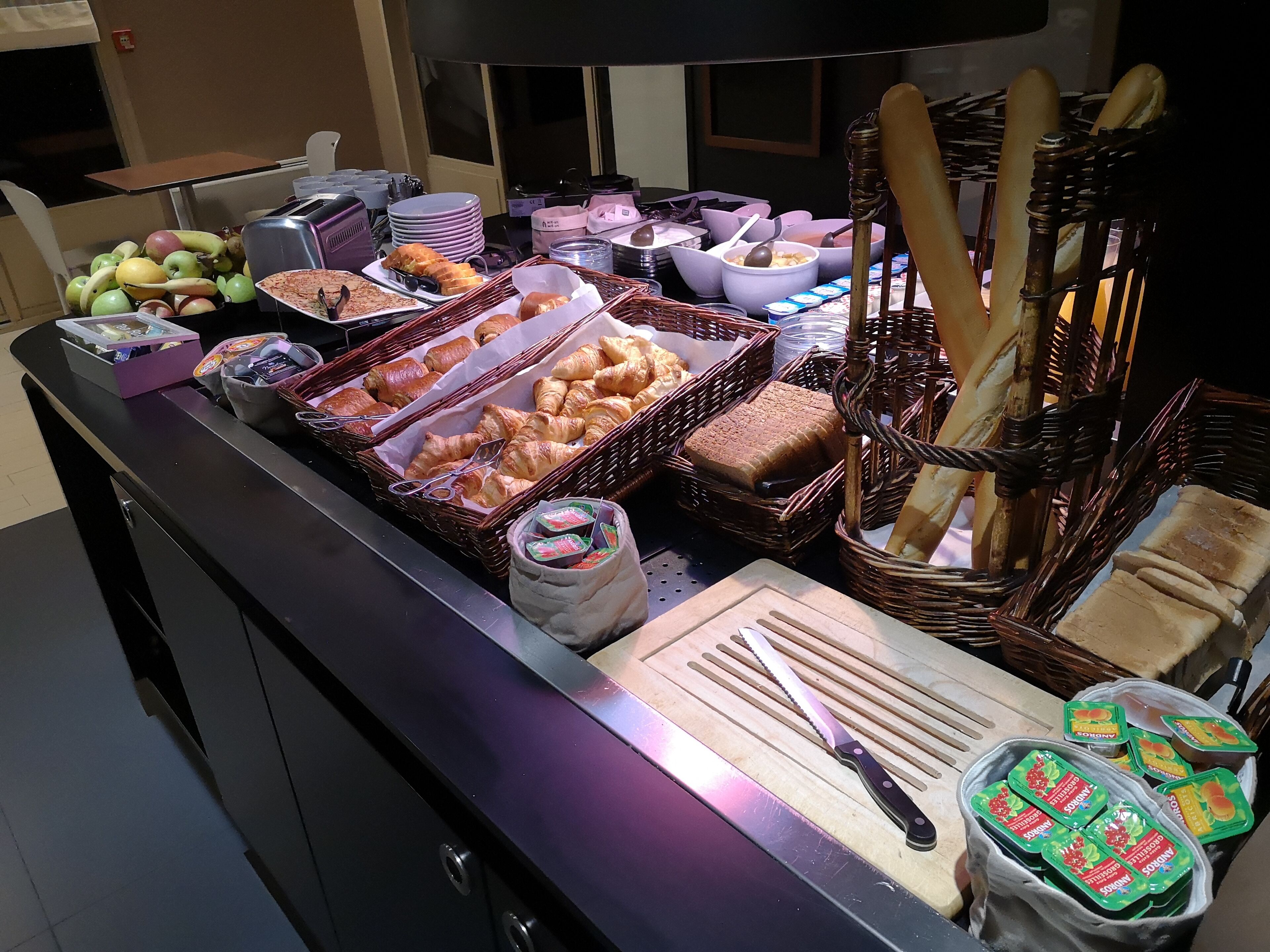 Buffet com diversos alimentos, incluindo frutas, pastelaria e acompanhamentos.