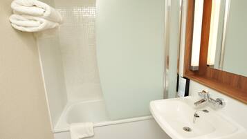 A bathroom with a bathtub, a sink, and a towel rack with towels.