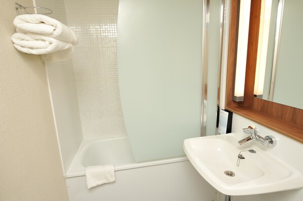 A bathroom with a bathtub, a sink, and a towel rack with towels.