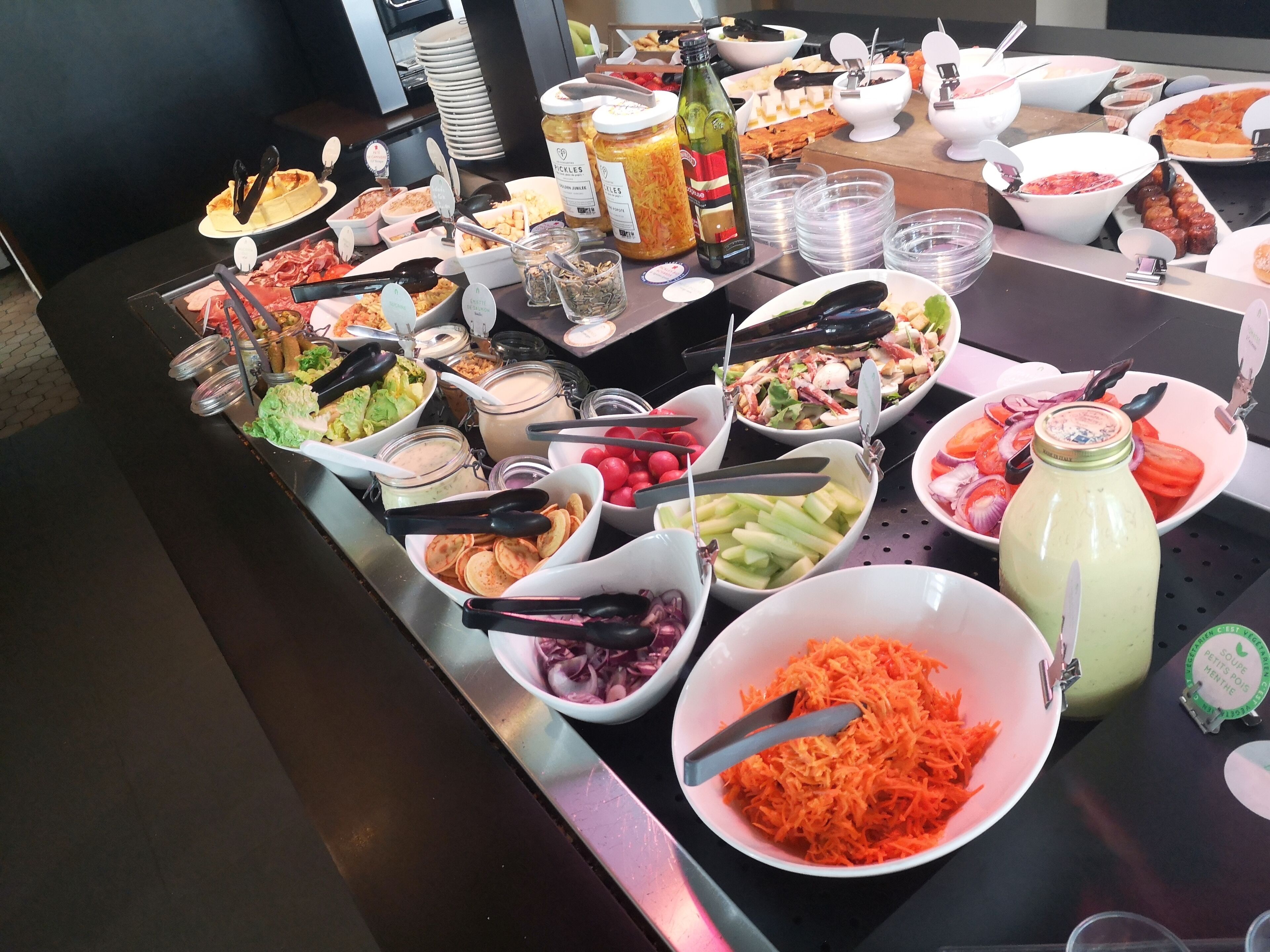 A buffet table with various food items and condiments.