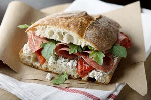 A sandwich with various ingredients on a piece of bread, placed on a paper wrapper. - Campanile Pont A Mousson (Lesmenils)