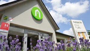 Un hotel con un logotipo verde, un letrero rojo que indica un restaurante y un anuncio para el restaurante del hotel.