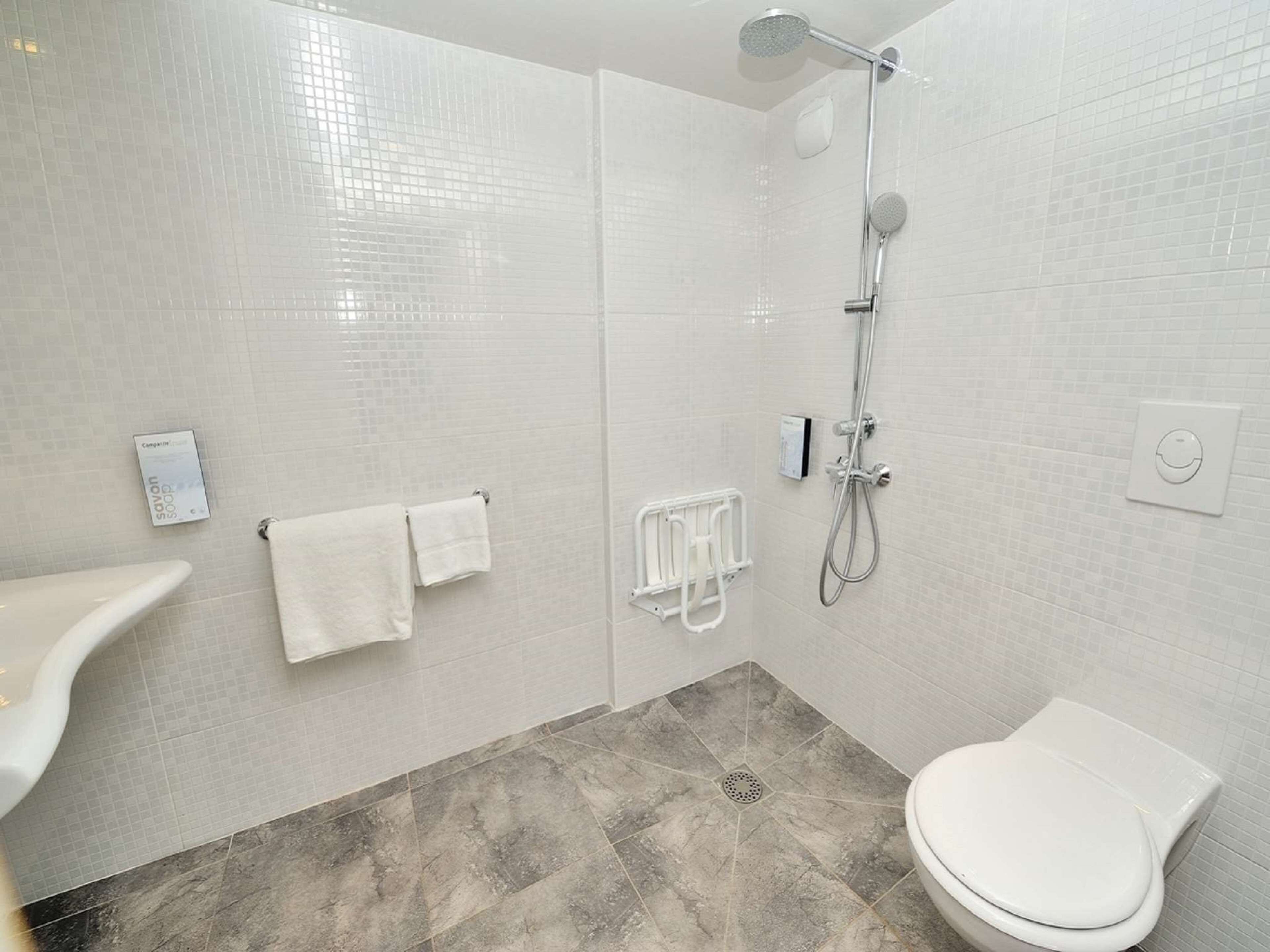 Un baño moderno con ducha, inodoro y perchero.