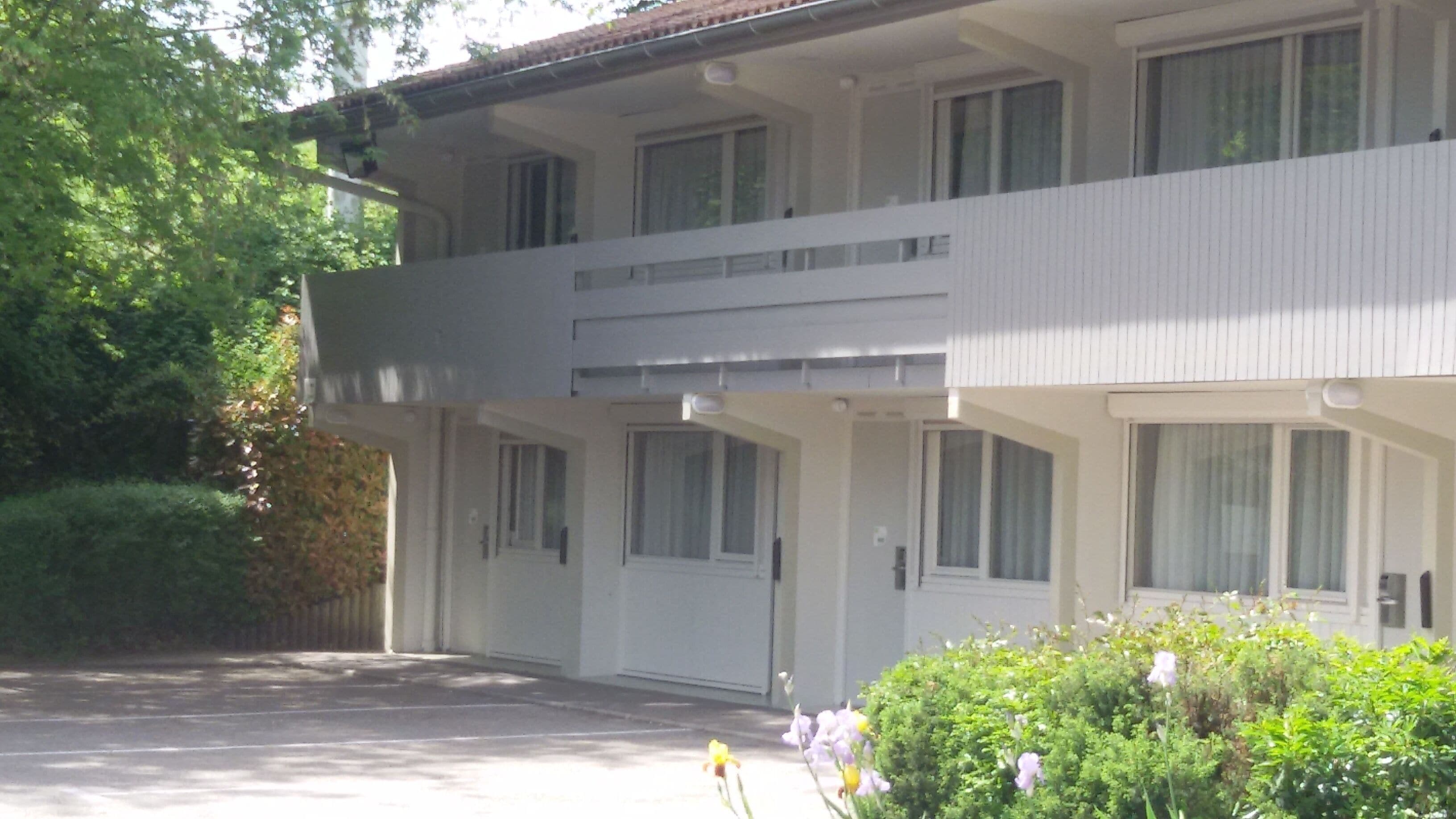 A two-story building with a flat roof and a balcony on the upper floor.