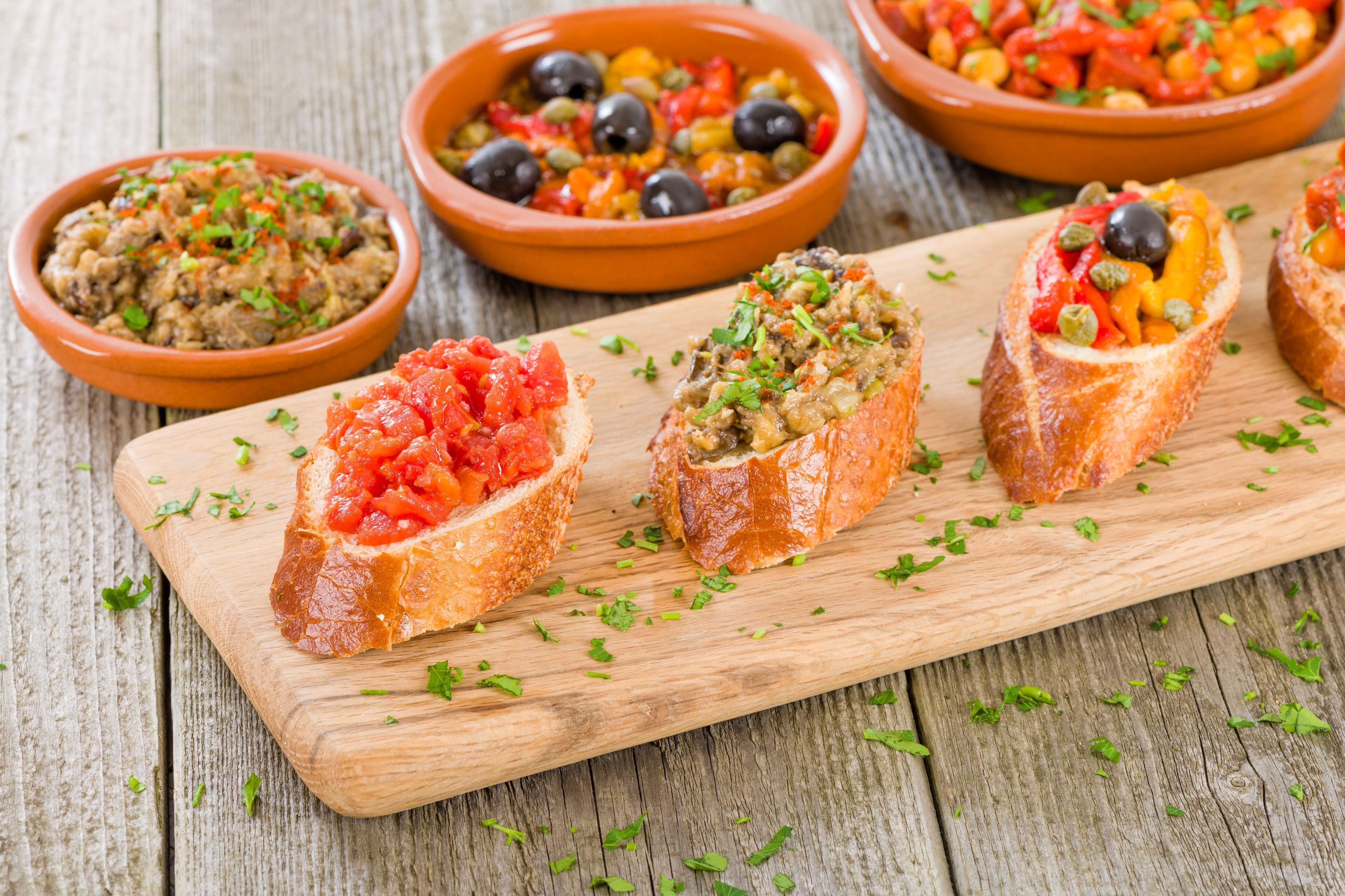 Una tabla de madera con cuencos de pan que llevan diferentes ingredientes.