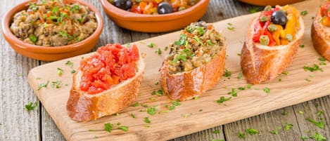 Una tabla de madera con cuencos de pan que llevan diferentes ingredientes.