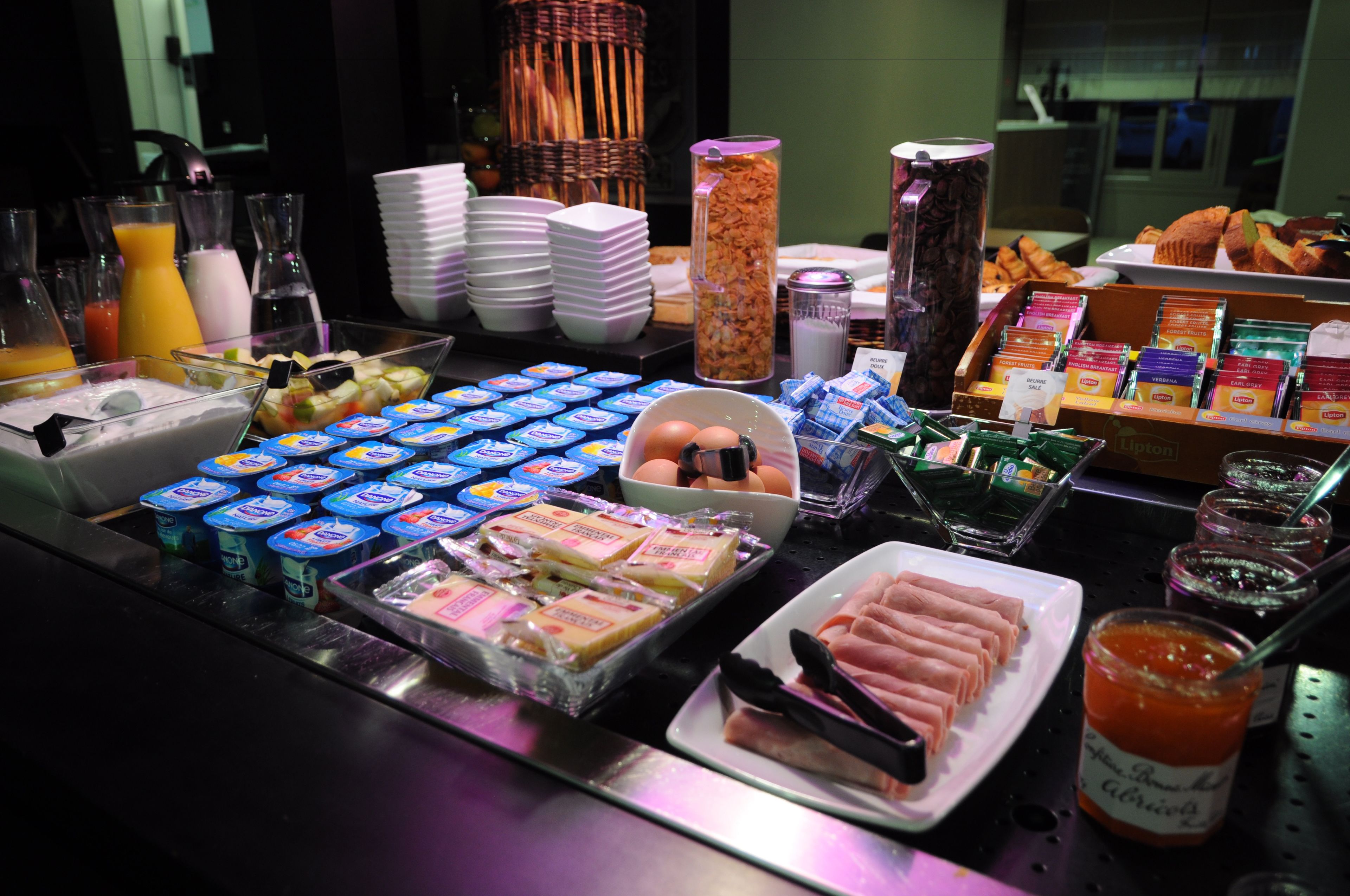Un bufé con diferentes opciones de comida, incluyendo yogur, huevos y bollería.