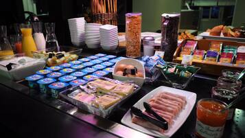 Un bufé con diferentes opciones de comida, incluyendo yogur, huevos y bollería.
