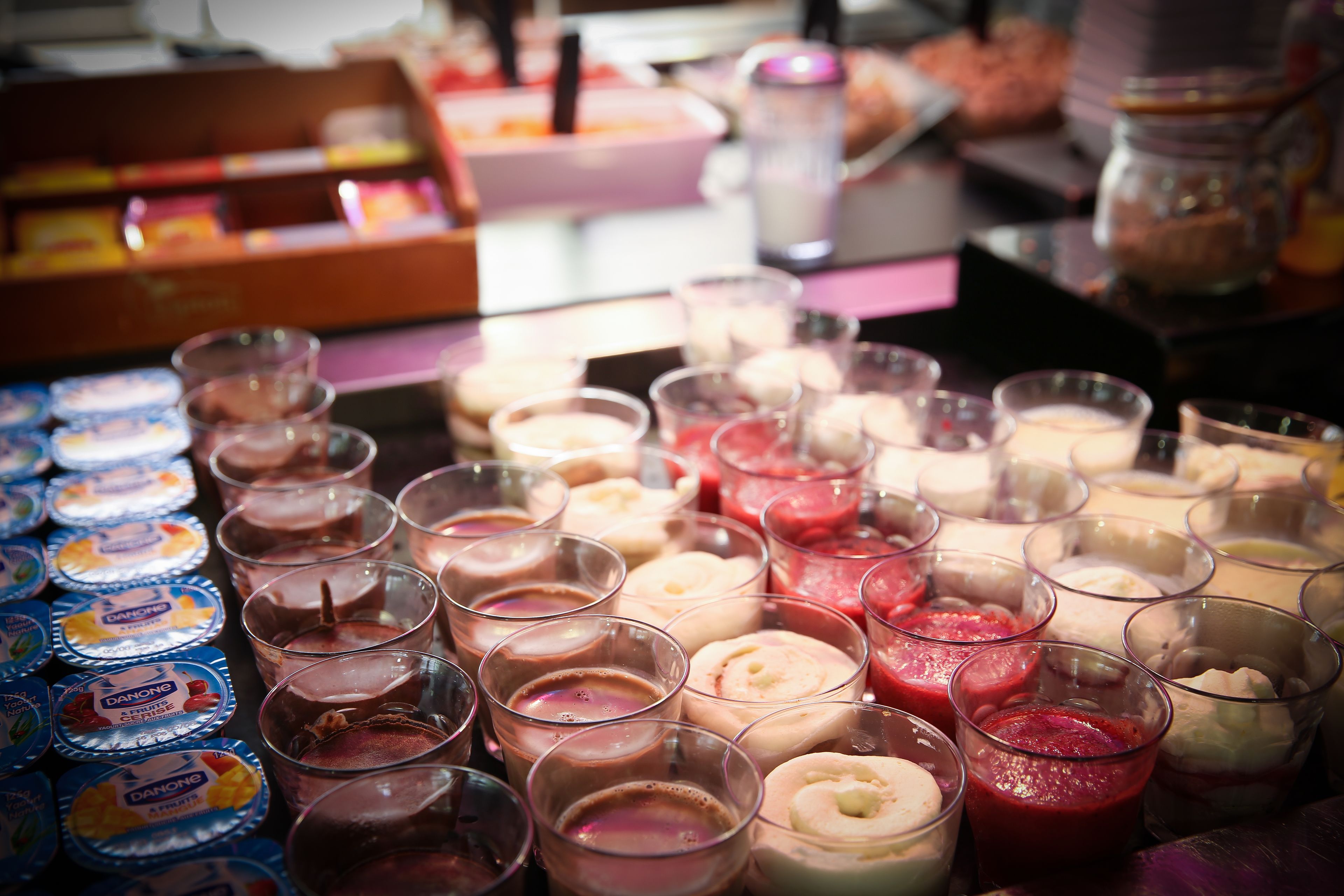 A variety of beverages in glasses and containers, including Danone products, on a table.