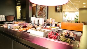 A buffet with various food items and a large hanging light fixture. - Hôtel Inn Design & Restaurant Nantes (Sainte-Luce-sur-Loire)