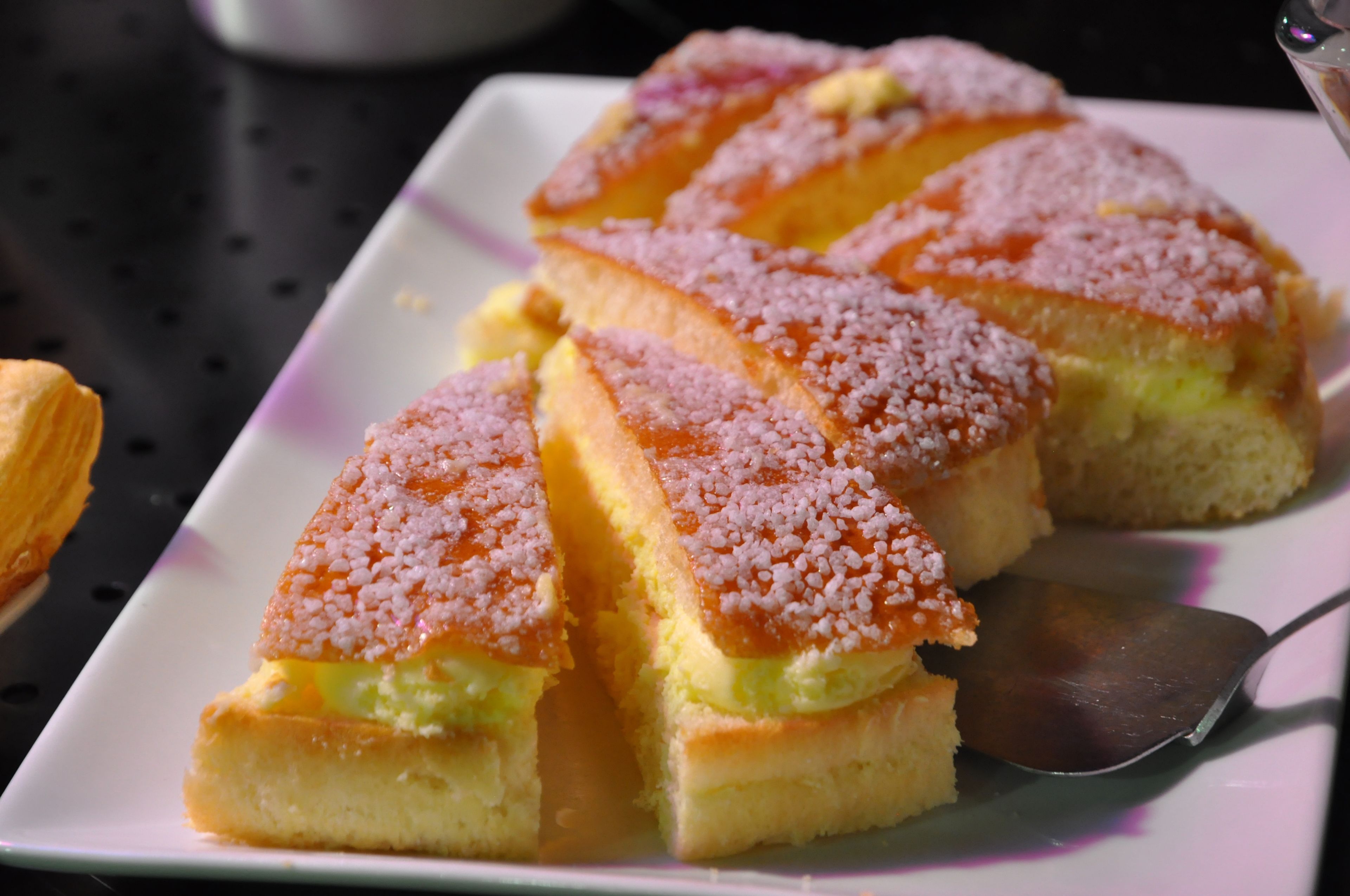 A plate of triangular pastries with a pink topping, served on a white plate with a spoon.