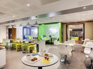 A modern dining area with a central island, white tables, and colorful chairs.