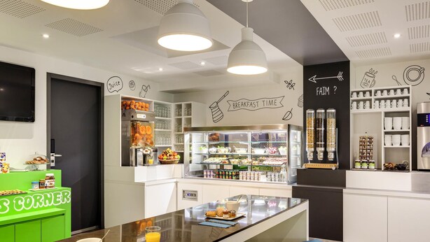 Una barra de desayuno moderna con una máquina de café, dispensador de zumo y diversas opciones para desayunar.