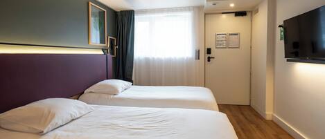 A hotel room with two beds, a TV, and a door leading to a bathroom.