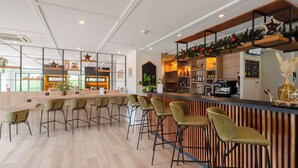 A modern bar area with wooden flooring, bar stools, and a counter with a coffee machine. - Campanile NATURE - Metz Sud Jouy aux Arches (Jouy-aux-Arches)