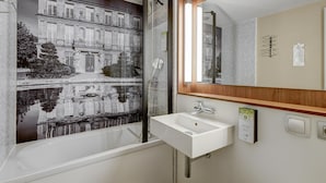 Un baño con un espejo grande, un lavamanos blanco y una ducha.