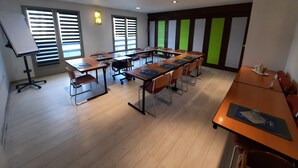 Un salón de conferencias con varias mesas, sillas y una pizarra.