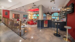 A modern hotel lobby with a bar area, seating, and a staircase with a decorative railing. - Promotel Carros (Carros)