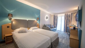 A hotel room with two beds, a sofa, a desk, and a TV. - Promotel Carros (Carros)