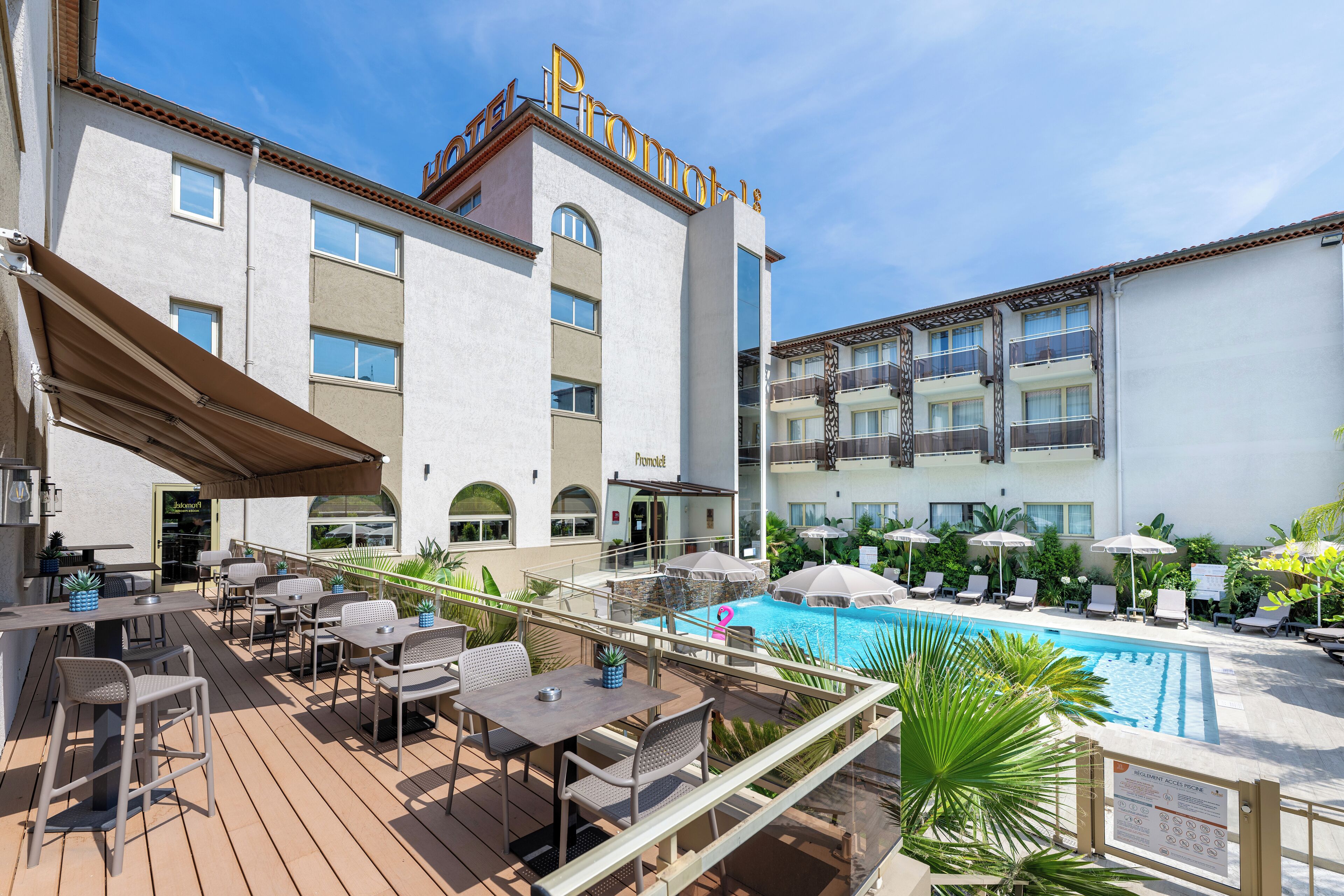 A hotel with a pool area, outdoor seating, and a sign indicating a swimming pool.