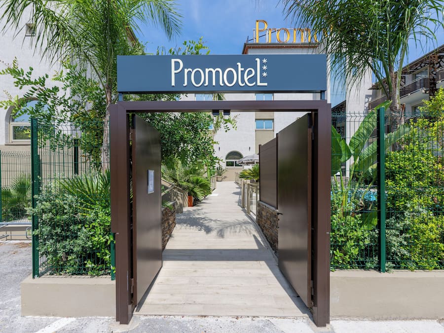A gated entrance to a building labeled 'Promotel' with a pathway leading to the entrance.