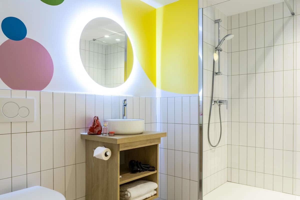 Un baño moderno con inodoro, lavamanos, ducha y espejo.