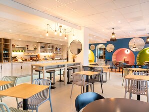 Una cafetería moderna con una barra central, diferentes disposiciones de asientos y espejos decorativos.