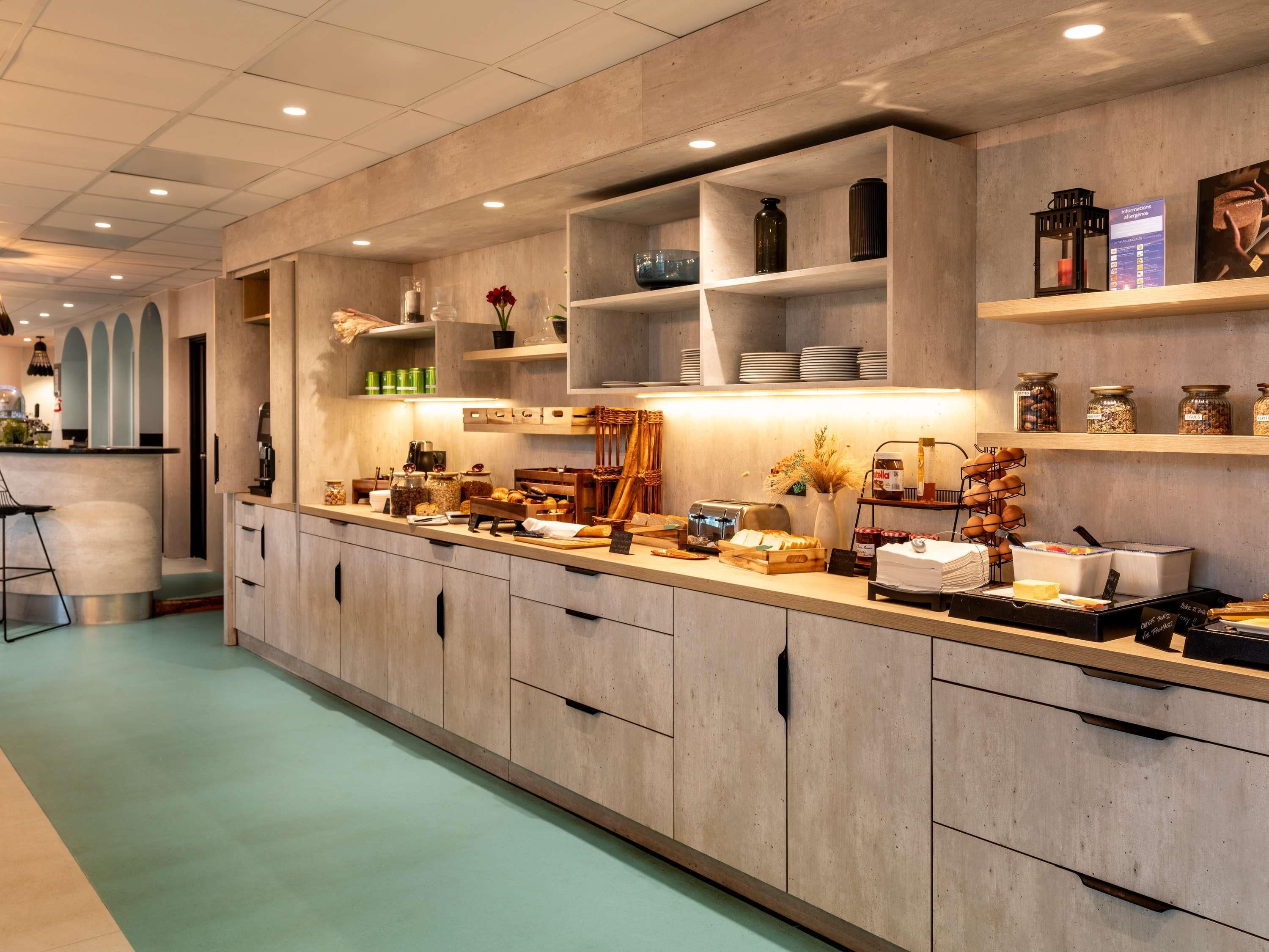 Een moderne keuken met houten kastjes, een bar en diverse etenswaren op planken.