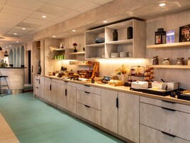 Una cocina moderna con armarios de madera, una zona de bar y varios alimentos exhibidos en estantes.