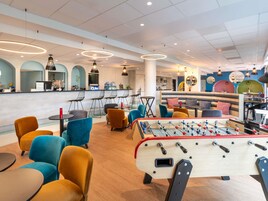 Un'area bar moderna con tavolo da calcio, posti a sedere confortevoli e un bancone.