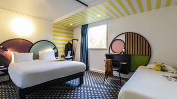 Camera d'albergo con due letti, una scrivania, una sedia, uno specchio e una finestra con tende.