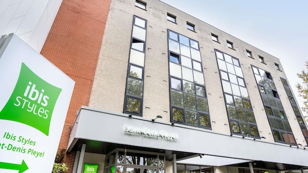 A building with a sign for 'ibis Styles' and 'Saint-Denis Pleyel'.
