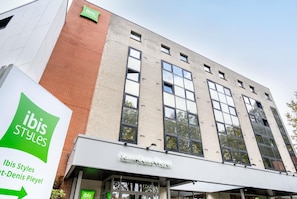 Een gebouw met een bordje waarop 'ibis Styles' en 'Saint-Denis Pleyel' staan.