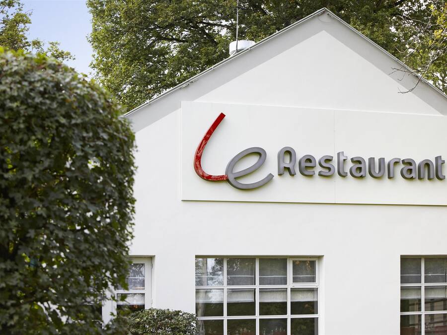 A building with a sign that reads "Restaurant" and a red curved design element.