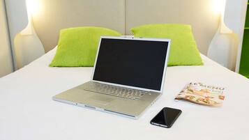 Een laptop op een bed, met een tijdschrift en een smartphone ernaast.