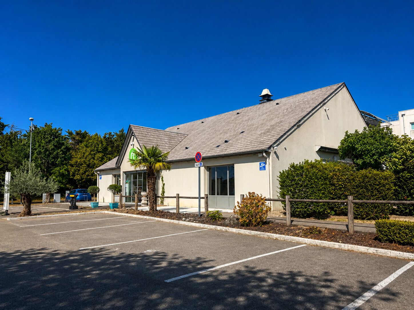 A building with a sloped roof, a parking lot, and a clear blue sky.
