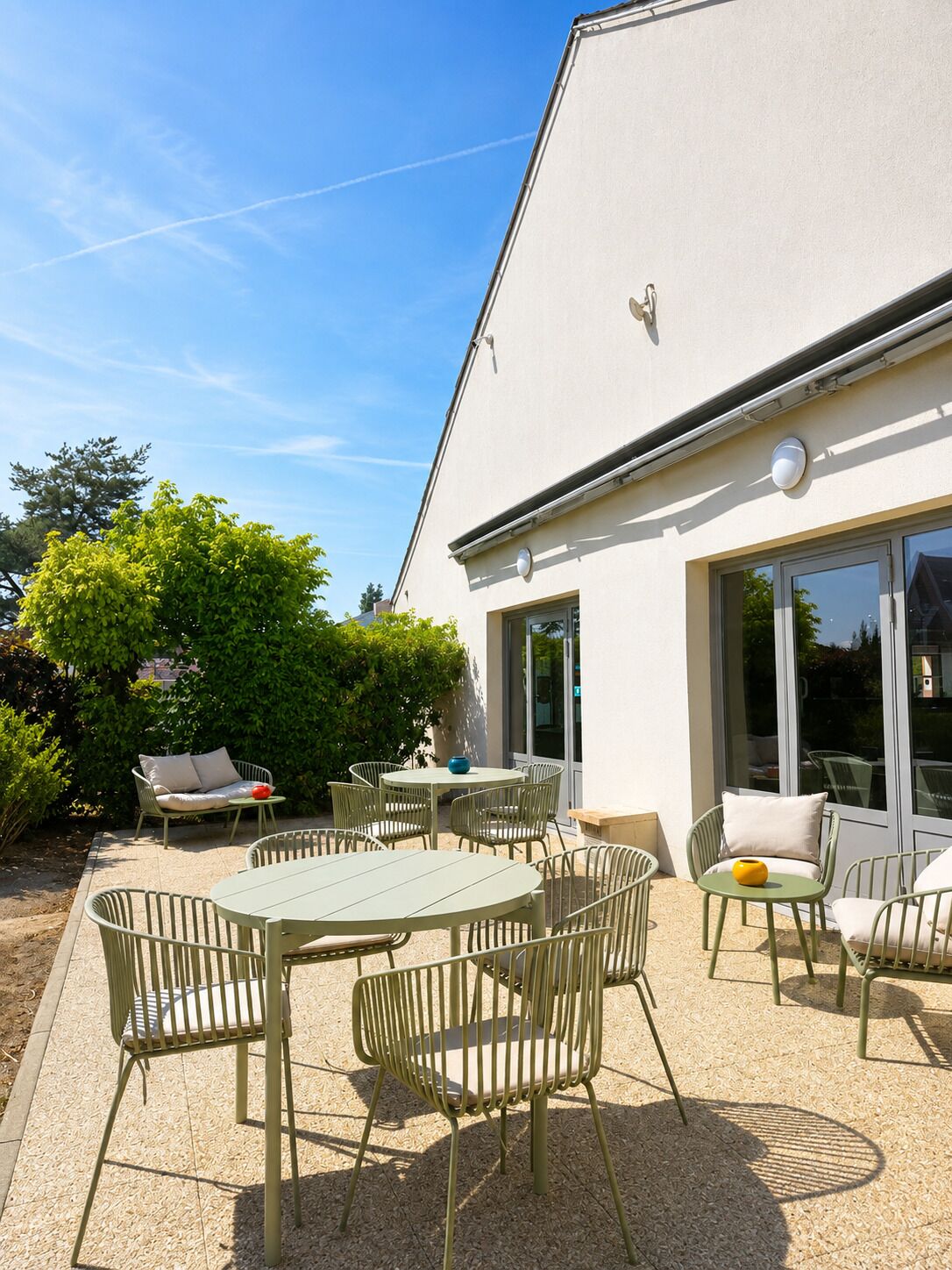 Un espace extérieur aménagé en terrasse, avec une table et des chaises, un canapé et une plante en pot.